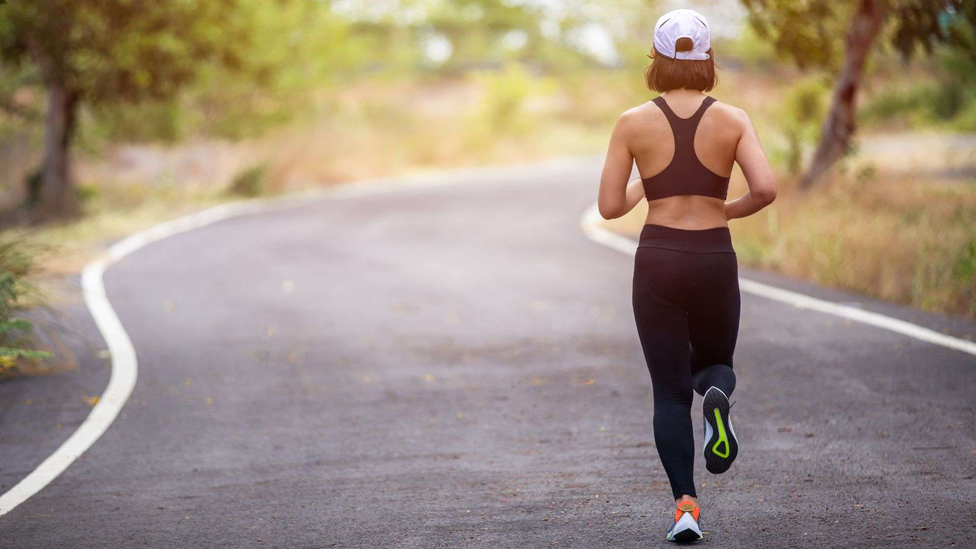 back of woman jogging down street