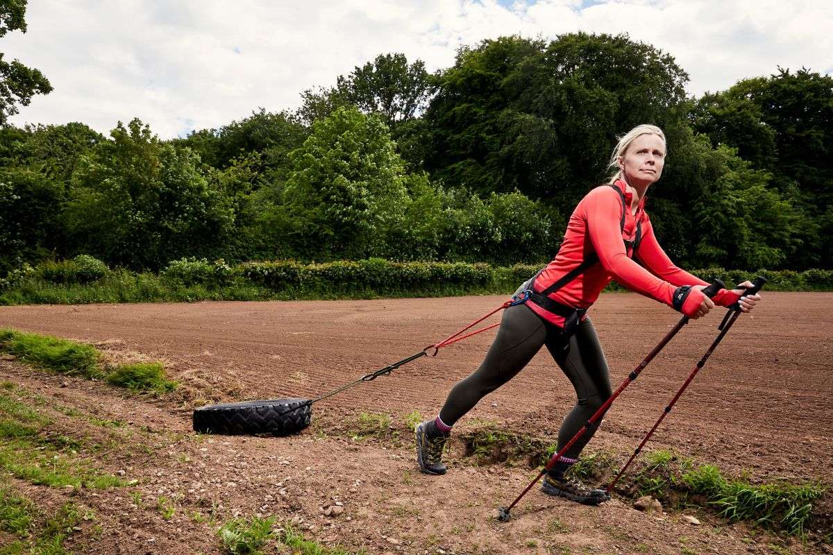woman in red shirt pulling a tire after her