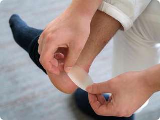 Somebody putting a blister plaster on their heel