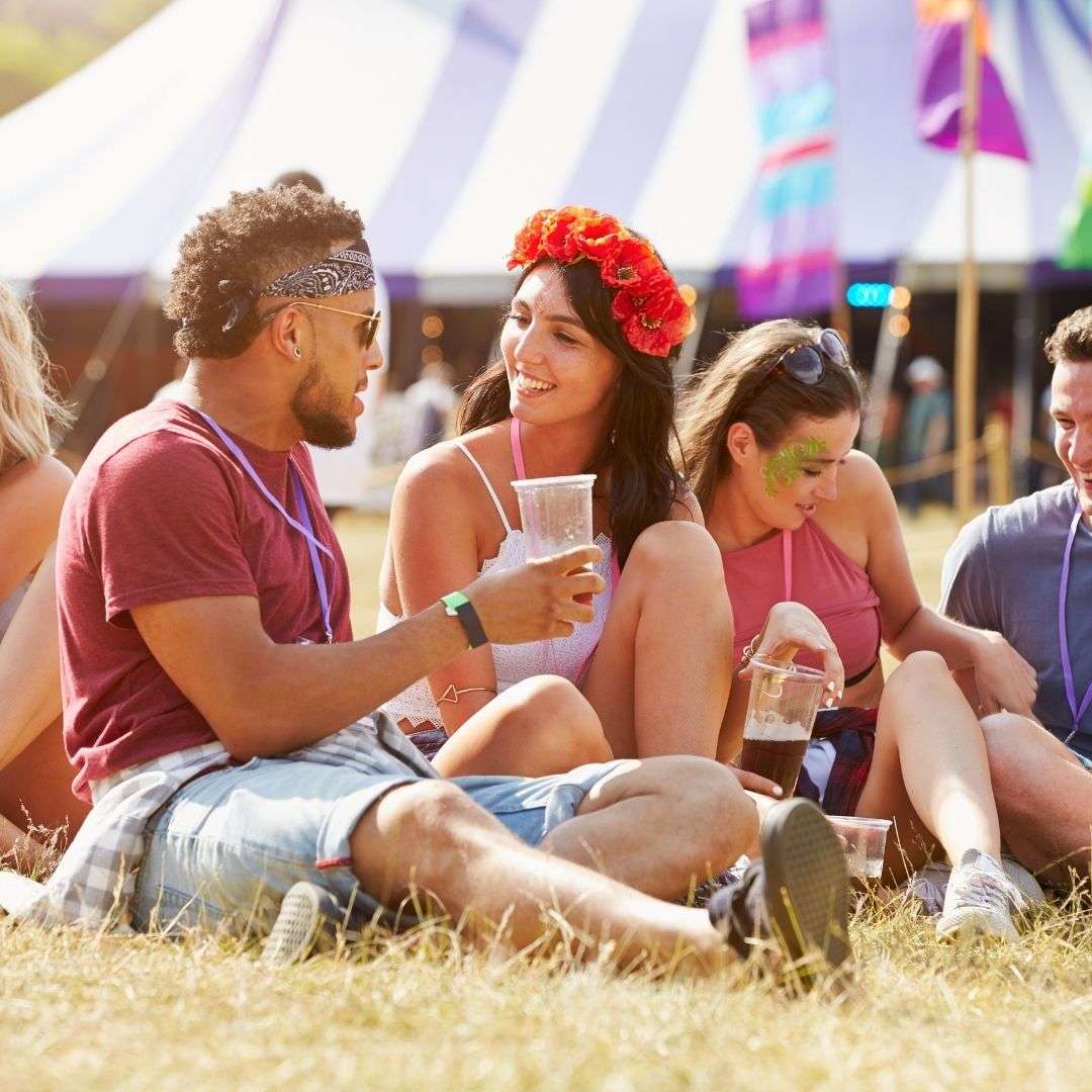people sitting in grass at festival