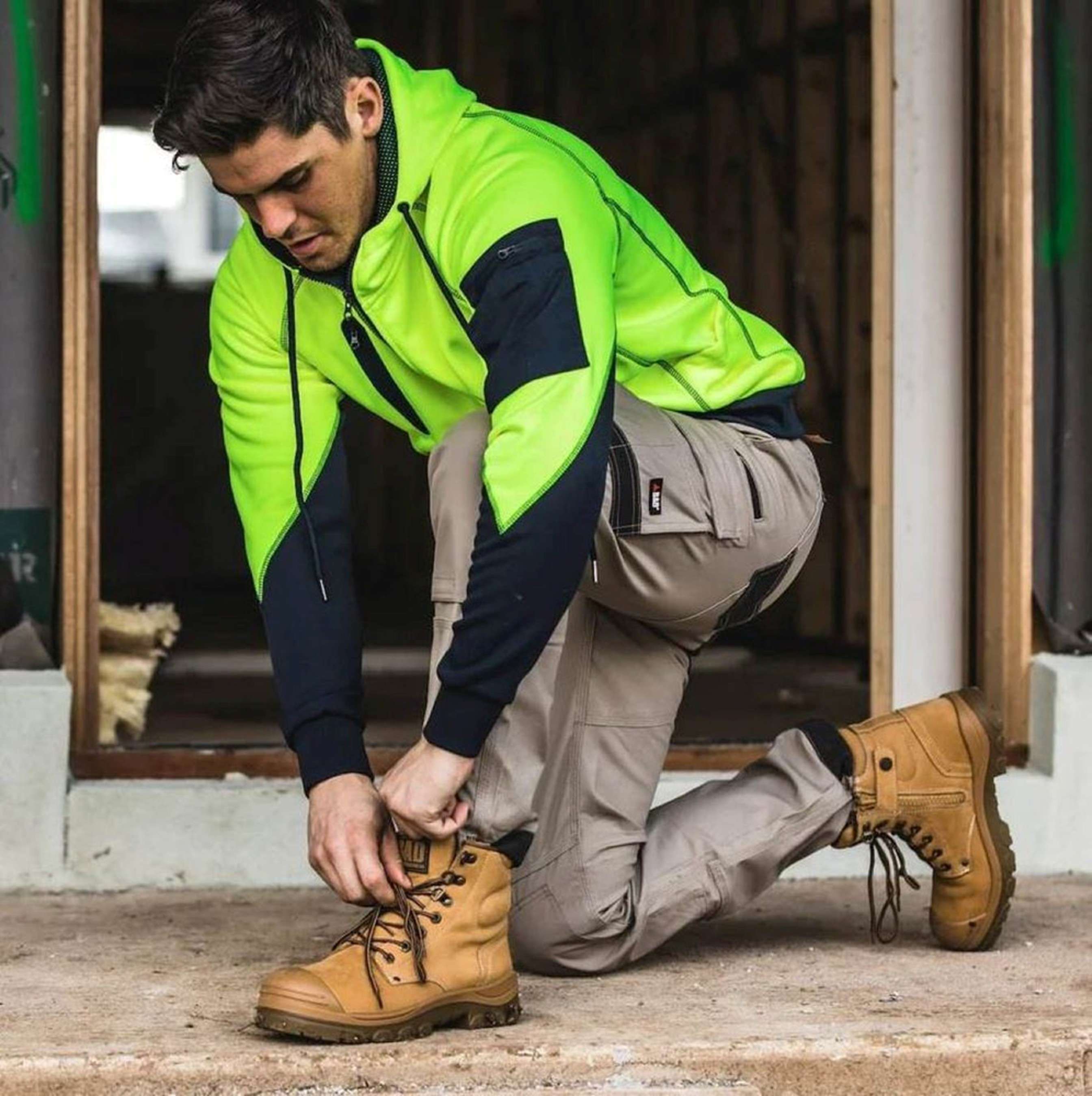 Worker adjusting work boots to prevent heel blisters during long shifts.