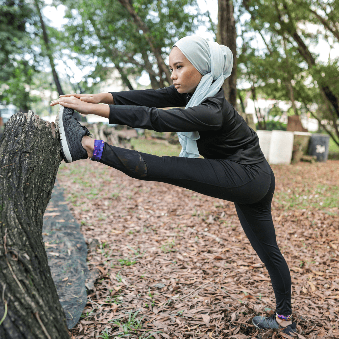 woman with head scarf stretching in park